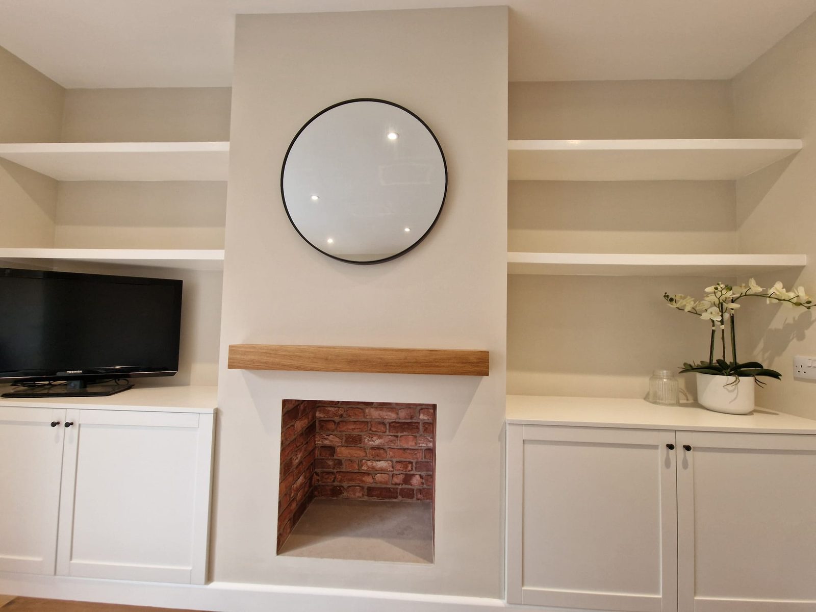Alcove units with white cupboards, floating shelves and an oak mantel beam