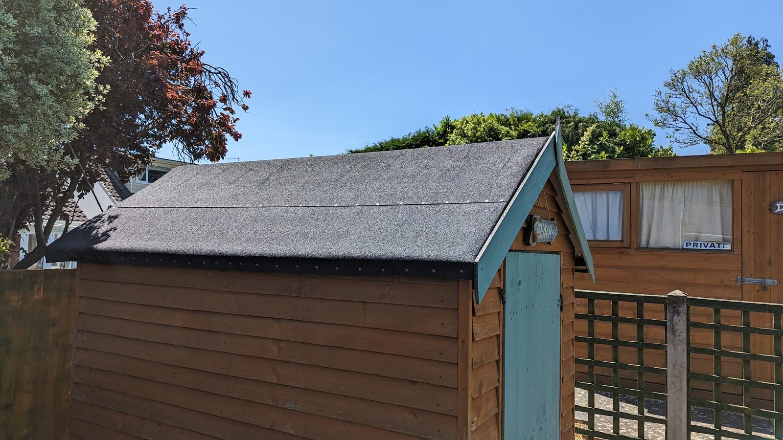 Timber garden shed with a felt roof and teal door