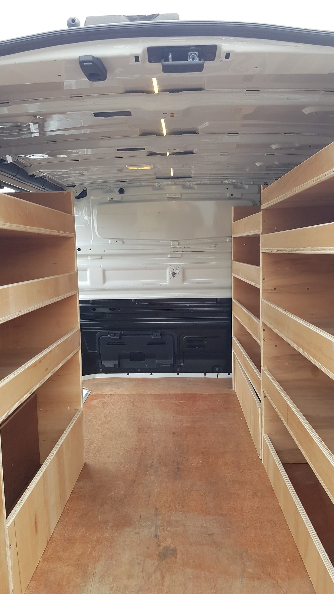 Plywood shelving fitted inside a van, seen from the cab end