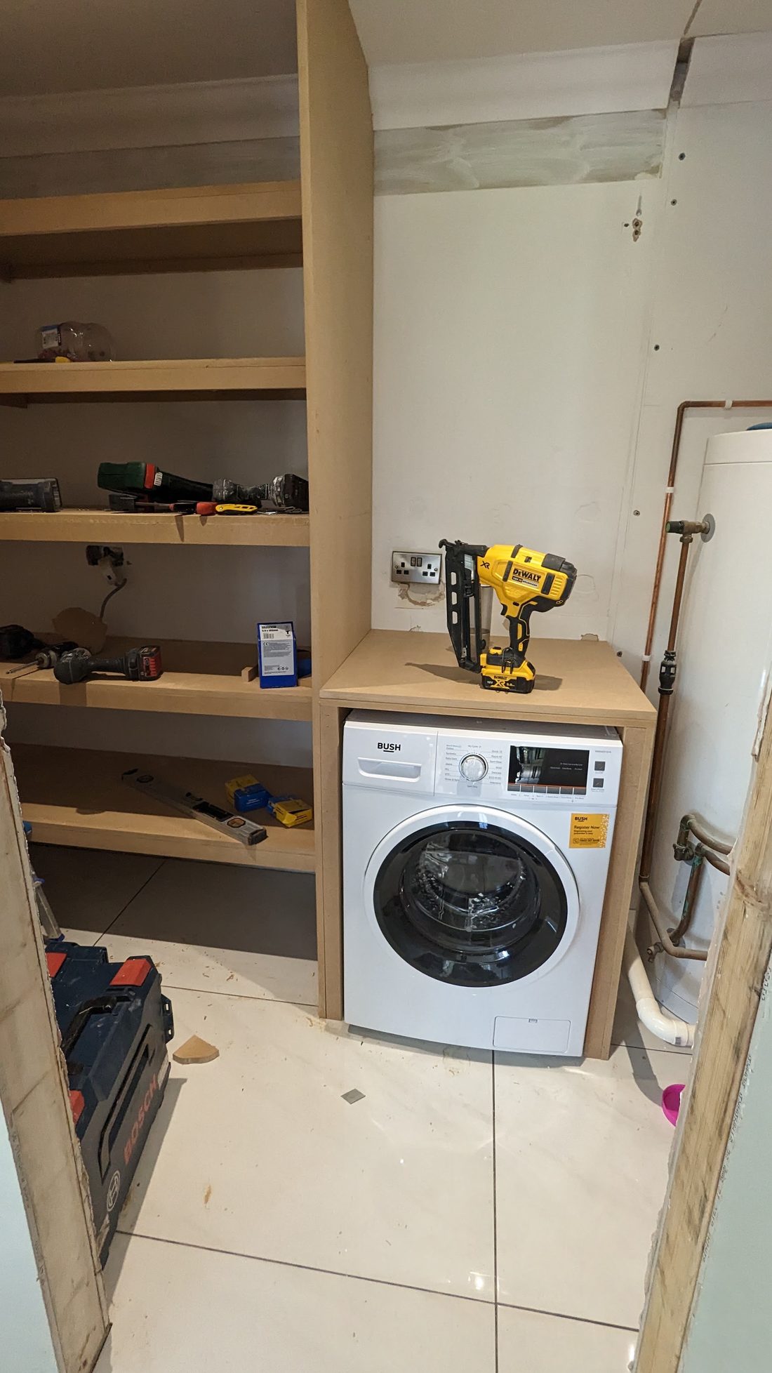 Built-in shelving and a housing around a washing machine in a utility room, mid-build