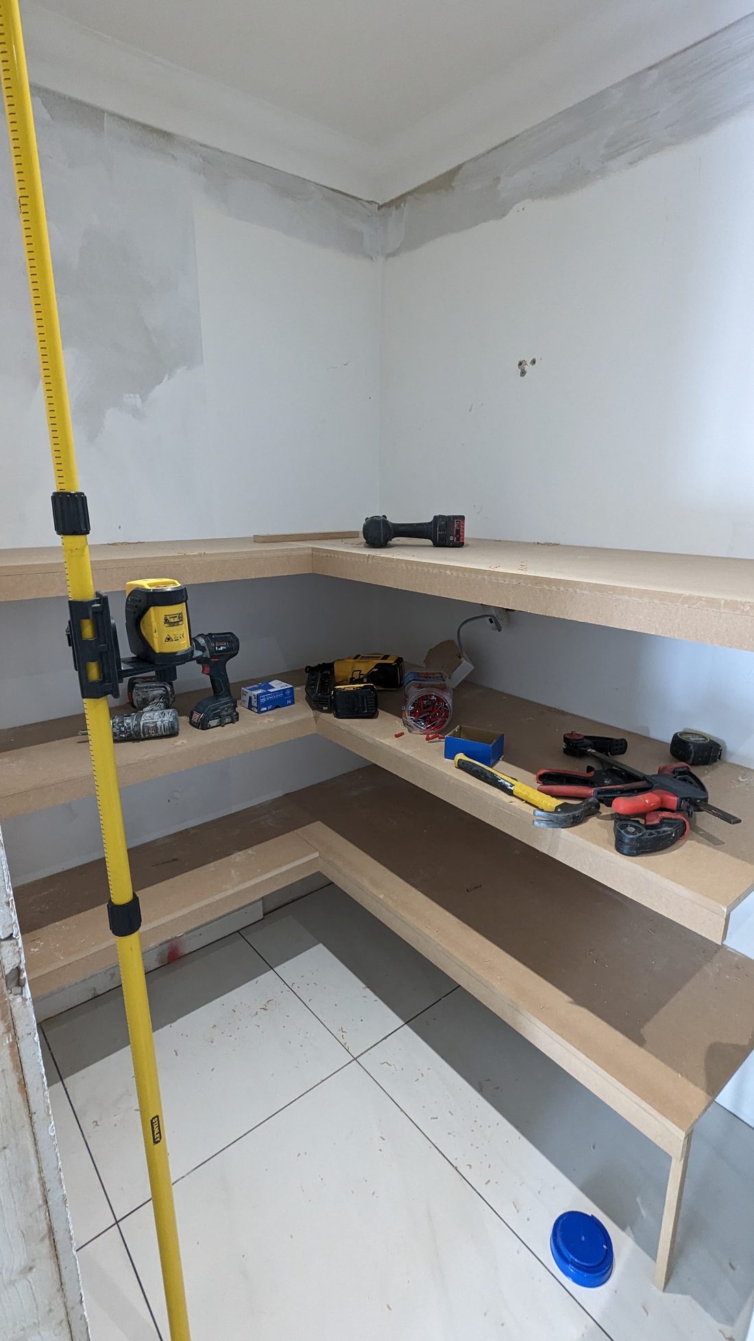 L-shaped built-in shelving going into a store room, with tools on the shelves